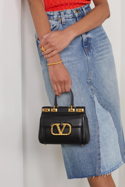 Valentino Garavani 这款精巧雅致的 “Alcove” 硬质手提包以纹理皮革制成，触感会随着时间推移愈加柔软，四枚脚钉能避免包底刮花磨损。打开包袋的瞬间，醒目的红色衬里便带来令人惊喜的视觉冲击。选择相衬珠宝并非…