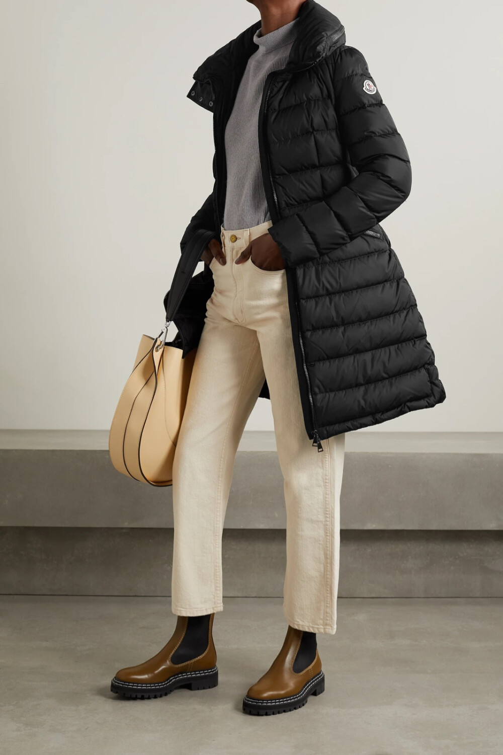 Moncler 这款 “Flammette” 外套巧妙结合了运动功能性和精裁服的优雅，无论在山野还是城市穿着皆宜。它采用耐磨的绗缝软壳面料制成，内里填充保暖羽绒，可收放的兜帽和压铸拉链方便实用。腰部省道和背面的松紧拼接片收束略微宽松的廓形。