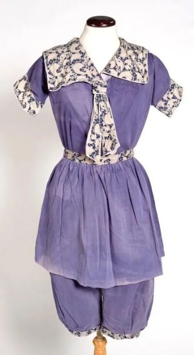 浴裙是帆布或法兰绒制成的及膝水手领裙装，腰间系有腰带以凸显轮廓，裙下配有灯笼裤。