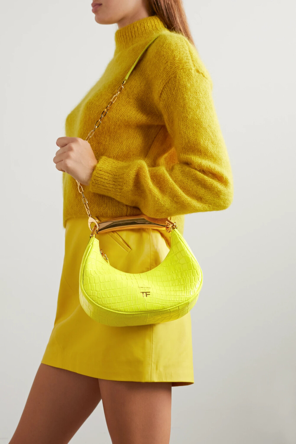 TOM FORD 这款 “Loop” 迷你手提包造型精巧，雕塑感金色手柄经过抛光处理后散发出亮眼光泽。单品以黄色仿鳄鱼纹皮革在意大利制成，弧形包身灵感源自 90 年代流行的法棍包，包内空间足以容纳你的手机、粉盒和钥匙。