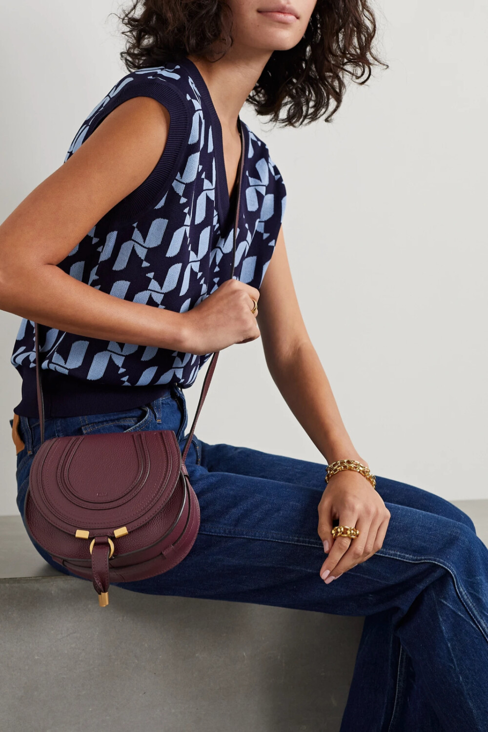 Chloé 的 “Marcie” 马鞍包是品牌最具辨识度的包款之一，本季的这一 “Eucalyptus” 灰绿色迷你版本更是抢眼之作。它以纹理皮革制成，点缀马术风车线和光洁的金色五金件。带贴袋的包内可存放各种出行必备。不妨调节肩带至理想长度背携。