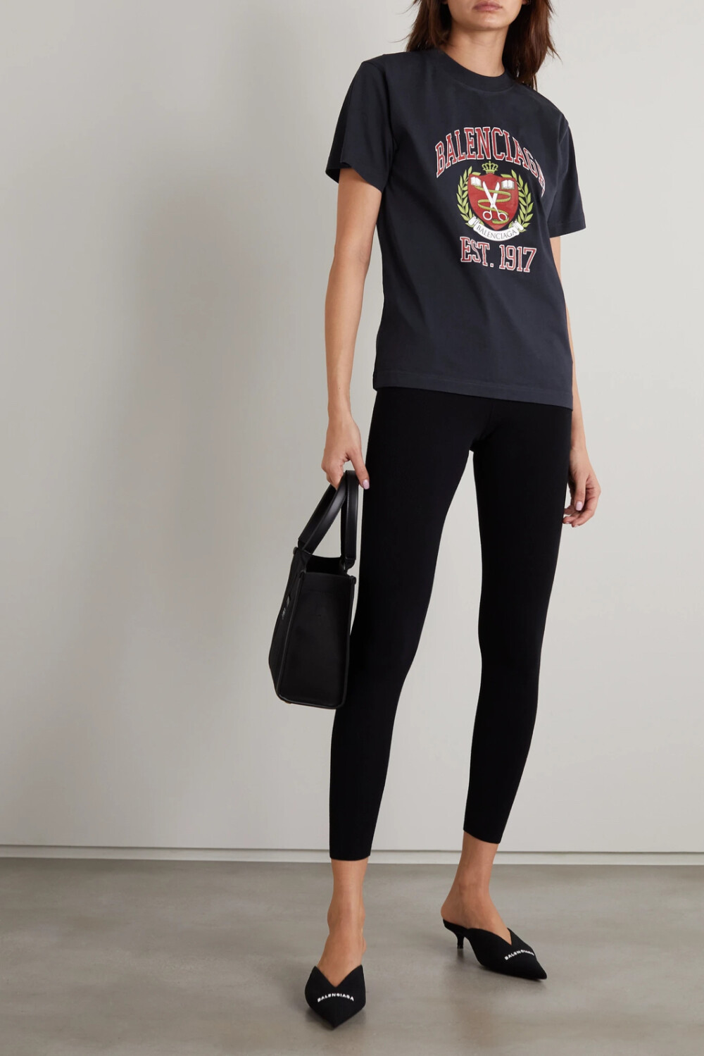 Balenciaga 这款 T 恤以柔软的纯棉平纹布制成，剪裁较为修身，设有细密罗纹边的宽幅圆领不易变形。衣身正面的徽章印花散发出浓郁的学院风气息，卷尺与裁缝剪刀巧妙暗示了时装屋精湛的高定匠艺。