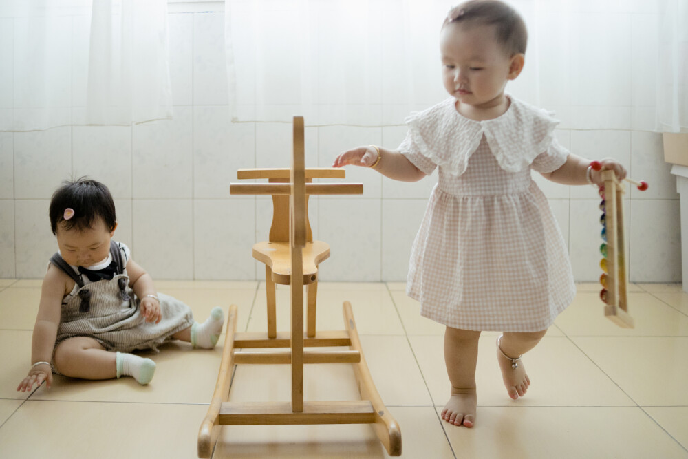 你们仨
摄影：洪小漩
出镜：团子、樱桃、菲比
6月底，尚且在租住的房子里生活，天气也还是炎热。
燕子和阿礼带了各自的孩子来家中玩耍。一张小木马，就足以让不满周岁的菲比和两个一岁半的小姐姐玩得很开心。相比另外两人在房间内窜来窜去，菲比实力有限，仅能扶着木马站起来张望。
虽然孩子们不过豆丁点大，却是各自有着各自的秉性。或许是受到燕子夫妻启发，团子语言方面有着惊人天赋，已经能说些长长短短的句子。而小樱桃动手能力极强，对于自己的目标似乎十分明确，拿着东西就要往姐姐妹妹手里塞。至于菲比，在我看来就是懵懵地，眼睛跟着两个小姐姐忙碌的身影滴溜溜转，似乎有些忙不过来。
小朋友果然是一种神奇的存在。