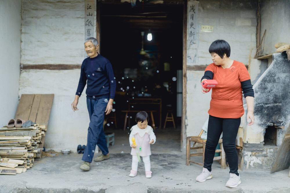 承欢阿太膝下
摄影：洪小漩
出镜：家人
小家装修好不多时，为了安全起见，还是决定暂且送菲比回了乡下小住几周。先是在阿科外婆家待了两周。上周末，我们赶回去从外婆家提上大包小包的行李，转而改道去了阿科爷爷奶奶家。
阿科说，每次和奶奶电话，她总问起，宝宝什么时候回来。这不，终于遂了老人家的心愿了。
菲比要唤爷爷奶奶为阿太，她的到访，老人家十分开心。不过，相比满眼宠溺的阿太，13个月的菲比总是将注意力放在对她爱答不理的土鸡和小黄狗身上。把吃食的鸡撵得满院子跑不说，还硬是想将挂在脖子上的哨子塞进狗嘴里，把狗子逼得见她过来便要绕道走。
一回家，阿科就爱让女儿骑在肩头，扛着她在村中溜达来去。仅有