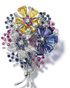 蓝宝石和红宝石花胸针由梵克雅宝（Van Cleef＆Arpels）。胸针上的红宝石、蓝宝石以及祖母绿被切割成特殊的形状，这种切割方式可以在侧面形成一个光和影的反差和反射光，使它如同一面镜子，把这些宝石也是通过特殊的镶嵌工艺安上去的，它们紧挨着彼此却看不见金属底座。