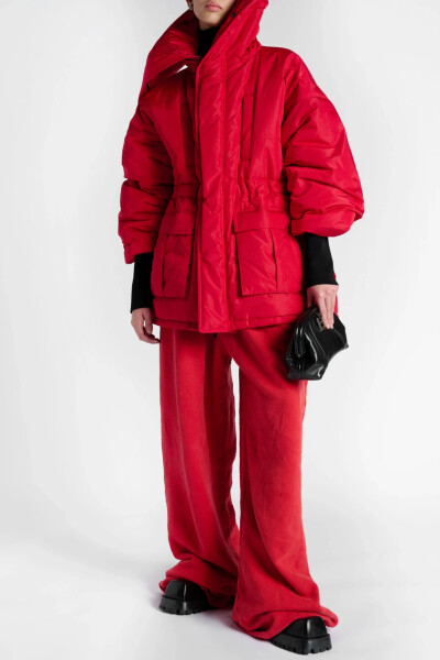 Balenciaga 这款 “CB” 外套以红色格子布裁就，版型宽大，内设填充物以进一步提升保暖性能，富有雕塑美感的超大衣领既可向外翻折，也可向上竖起，巧妙致敬了时装屋的高定传统。
