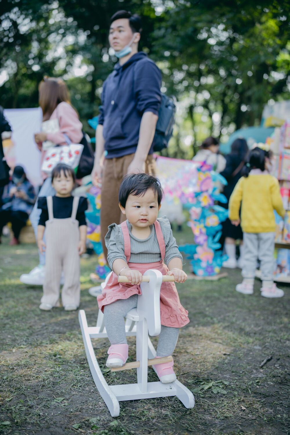 秋日去森林里赶了一个暖洋洋的集市
摄影：洪小漩
出镜：家人
场地：植物园
这是我初次带着菲比去参与杭州的集市。
杭城是个浪漫的地方，各种各样的展览，稀奇古怪的集市，很多都值得一去。
当日也是误打误撞到了植物园赶集。去的时候，人还不算很多。只是我缺乏一边带孩子，一边探索感兴趣事物的经验。
顾得住蹒跚学步的孩子，就分不开神去感受那些有趣的小铺子。
挣扎了一番，还是将看孩子放在了第一位。不过，整个活动氛围还是十分让人愉悦。待到阿科忙完工作，穿越堵车的街道抵达，我才得以坐下，听有趣的乐队轻吟浅唱。乐队成员说，能在森林里唱歌，是一件超妙的事。
对我而言，何尝不是呢。
