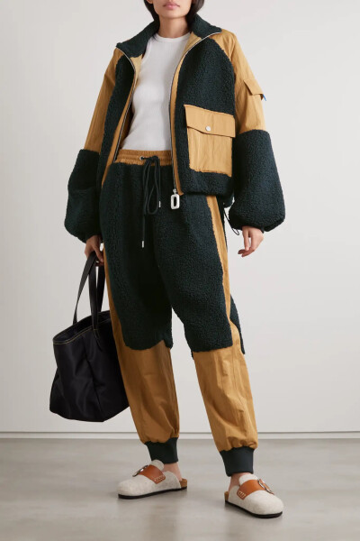 JW Anderson 2022 早春度假系列以壮美的大自然为灵感，设计上也融入了不少功能性元素。这款休闲裤裁自柔软的斜纹布，拼有毛茸茸的海军蓝色抓绒，收窄的裤脚营造出灯笼裤型。建议搭配配套飞行员夹克。