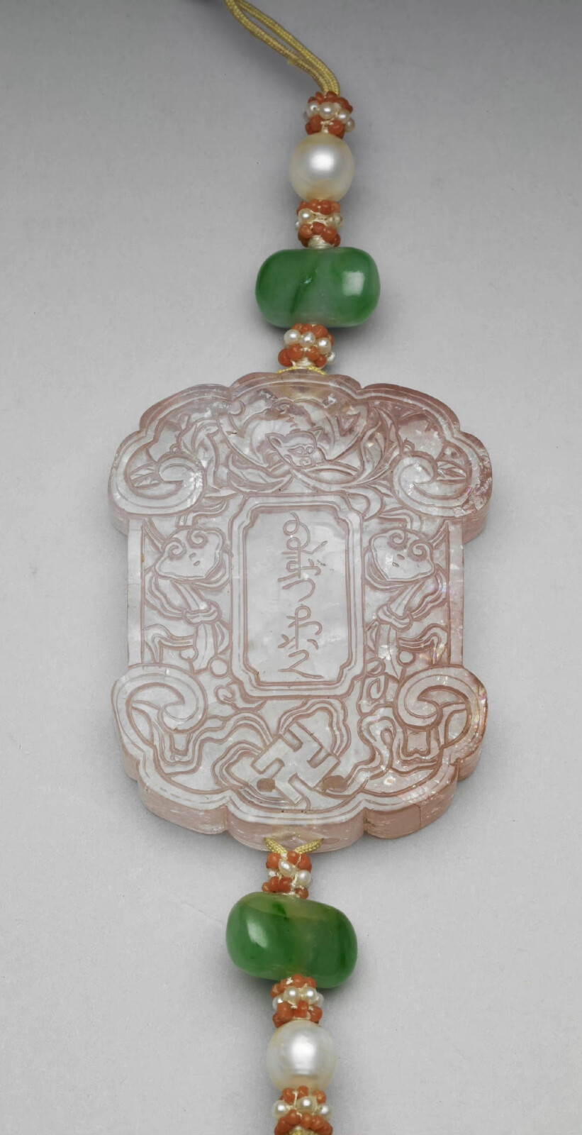 清 粉红碧玺斋戒牌，牌长5.15公分，长31公分，宽4.05公分，厚0.8公分，台北故宫博物院藏。
两面中央各刻“斋戒”及满文斋戒同义字，周琢螭蝠、卍、灵芝、桃纹等，上下繫黄线，贯饰珍珠、翠玉、红白米珠等，下端饰结子及缀旒苏。