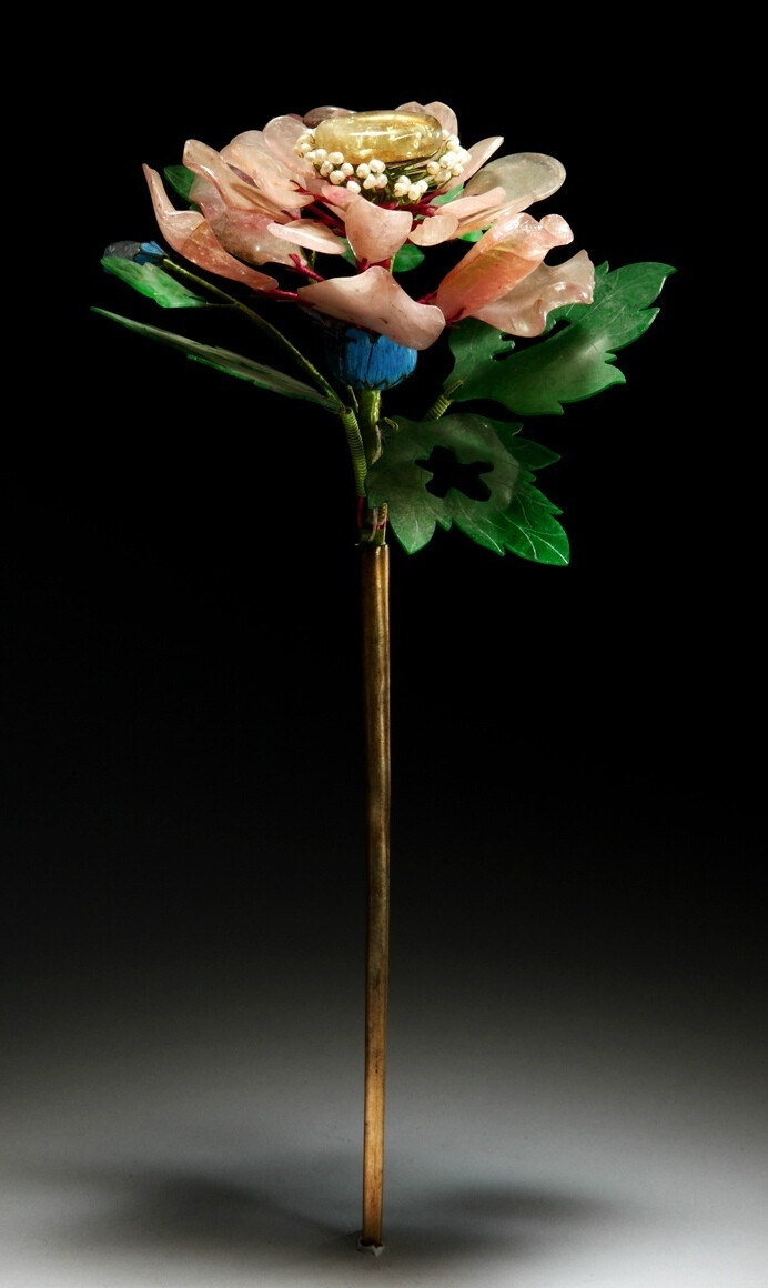 清乾隆镶宝石碧玺花簪，长25cm，宽12cm。花簪为铜镀金点翠，上嵌碧玺、珍珠、翡翠。以碧玺做立体芙蓉花，花蕊为细小米珠，花叶为翡翠薄片细雕而成，花蕾为碧玺雕成，花托为点翠。一只蝴蝶停落于芙蓉花上，其翅膀为翡翠薄片雕成，并嵌珍珠、碧玺。花簪使用了雕刻、金累丝、串珠、镶嵌、点翠等多种工艺，均细致精美，立体感强，彰显了皇家用品的尊贵。其中翡翠薄片的雕刻是广东宝玉石雕刻行典型的代表作，又称为“广片”，其特点是薄而匀、精而细，常用来雕刻花叶、蝴蝶翅膀。