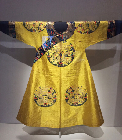 明黄色八团彩云金龙妆花纱单袍，清顺治，身长140cm， 两袖通长180cm，袖口15cm，下摆136cm，开裾长87cm，前胸后背团直径32cm，两肩团直径29cm，下摆前后团直径30cm。故宫博物院藏。 袍圆领，大襟右衽，马蹄袖，裾左…