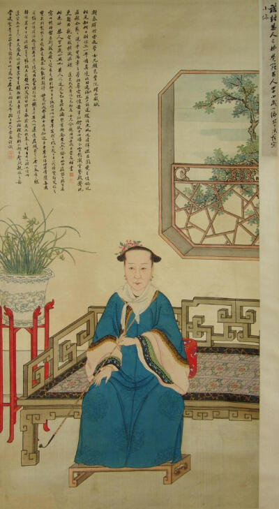 清 旗妇便服坐像 围领巾，身着蓝色团暗花便服，梳小两把头无珠翠，簪鲜花，落款同治年间，中国首都博物馆藏。 