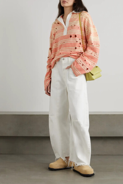 Acne Studios 这款 Polo 衫采用有机纯棉平纹布制成，经过石洗处理的面料质感柔软，带褪色效果的米色和橙色条纹散发久穿爱物般的复古韵味。遍布衣身的仿旧孔洞和落肩强调出松垮廓形。建议用它搭配白色阔腿裤。
