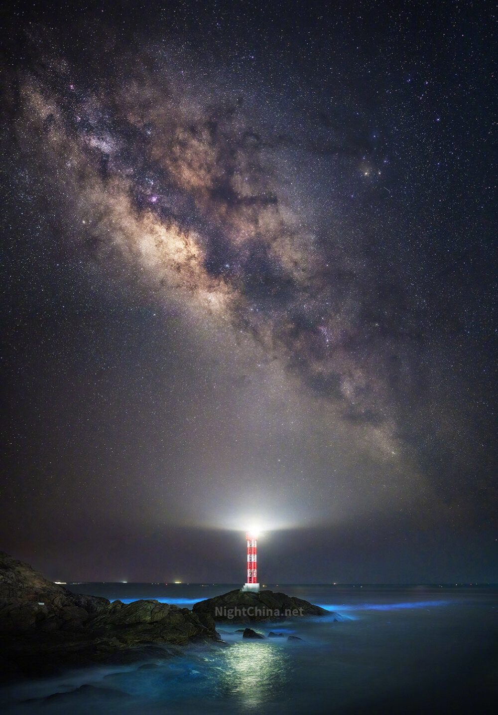 4月初春，随着南方升温，广东海滨出现了频繁的荧光海现象。夜间涨潮时，拍打礁石的海浪泛出蓝光，而灿烂的夏季银河正悬挂在渔港的灯塔上空。 摄影师@于海童_THU ，2022年4月4日摄于 广东 阳江海陵岛。索尼A7R4 + 索尼35 1.4GM镜头，ISO 1600，f/1.4，单张曝光13秒，6张全景拼接，海面部分多张堆栈