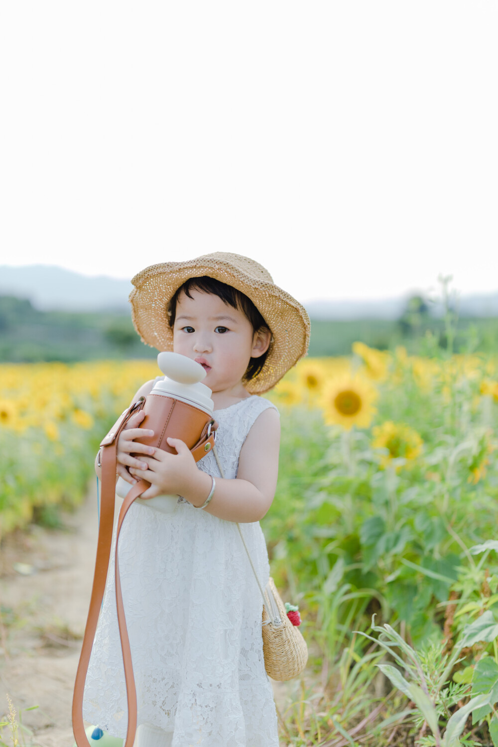 一眼好心情
摄影：洪小漩
出镜：菲比及家人
很小时候，我妈妈就曾种过一小片向日葵。
我太小，不知道那是自家的土地，放学后疯野到地里，站在巨大的花序下面，仰着头看着比我脸蛋子还大的一盘葵花籽，心想，什么时候可以吃。
后来，我将发现一片向日葵的事回家说与妈妈听，当她笑着告诉我那是她栽种的时，一股子莫名的骄傲在我心里油然而生。长大些，我才知道那是独属于我妈的浪漫。毕竟，只有她在自留地里栽种了一片明媚，耕种的人来来往往，都忍不住看两眼。
自此，我对向日葵有了执念。只可惜，我没有一片地像我妈那样可以自由栽种。
当得知杭州转塘有一片向日葵时，我便蓄谋，不论如何要带着菲比去看看。很幸运，成行了