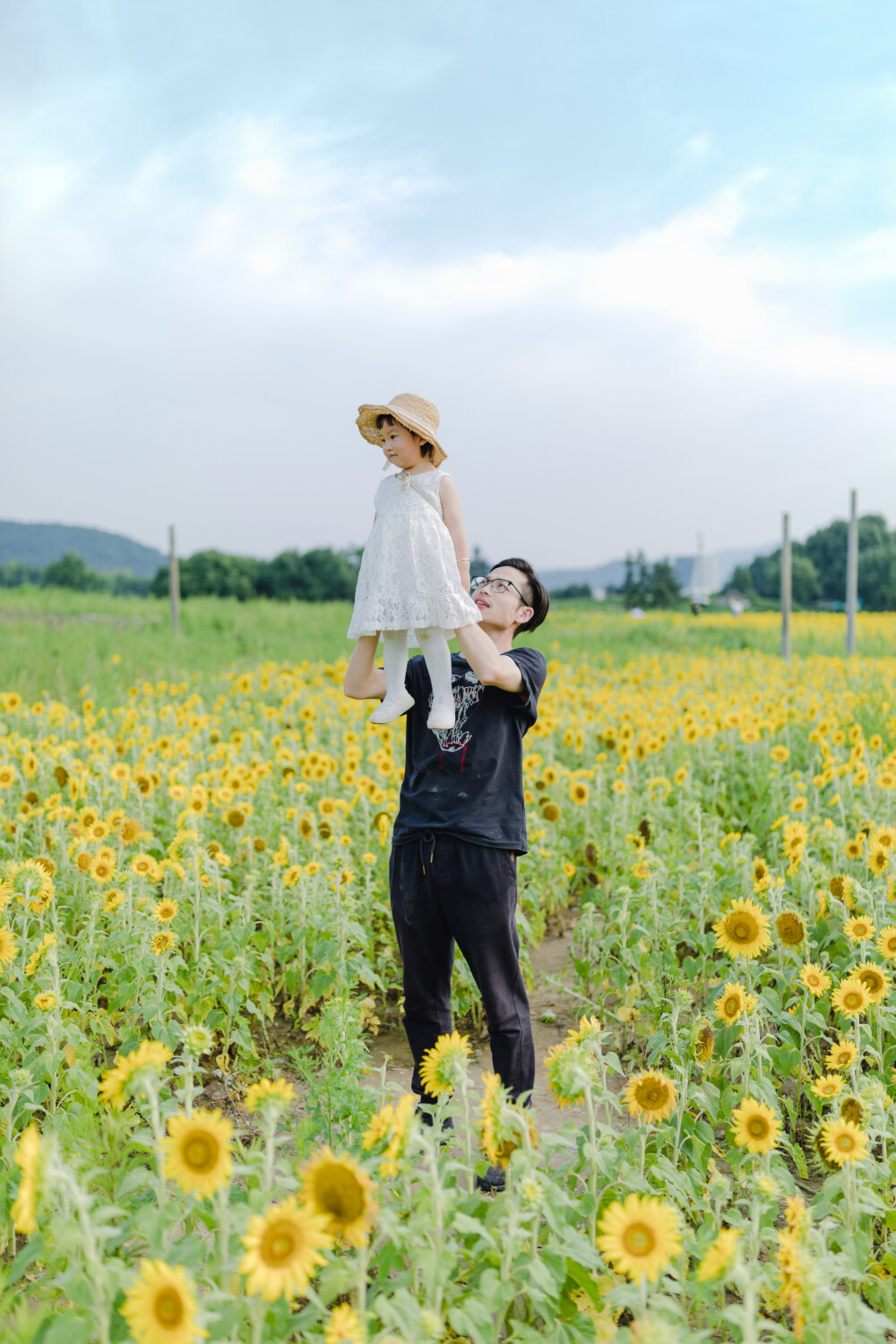 一眼好心情
摄影：洪小漩
出镜：菲比及家人
很小时候，我妈妈就曾种过一小片向日葵。
我太小，不知道那是自家的土地，放学后疯野到地里，站在巨大的花序下面，仰着头看着比我脸蛋子还大的一盘葵花籽，心想，什么时候可以吃。
后来，我将发现一片向日葵的事回家说与妈妈听，当她笑着告诉我那是她栽种的时，一股子莫名的骄傲在我心里油然而生。长大些，我才知道那是独属于我妈的浪漫。毕竟，只有她在自留地里栽种了一片明媚，耕种的人来来往往，都忍不住看两眼。
自此，我对向日葵有了执念。只可惜，我没有一片地像我妈那样可以自由栽种。
当得知杭州转塘有一片向日葵时，我便蓄谋，不论如何要带着菲比去看看。很幸运，成行了