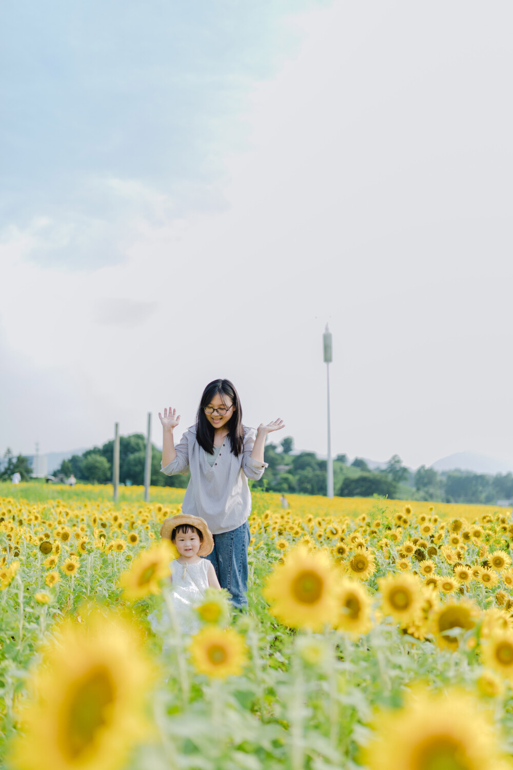 一眼好心情
摄影：洪小漩
出镜：菲比及家人
很小时候，我妈妈就曾种过一小片向日葵。
我太小，不知道那是自家的土地，放学后疯野到地里，站在巨大的花序下面，仰着头看着比我脸蛋子还大的一盘葵花籽，心想，什么时候可以吃。
后来，我将发现一片向日葵的事回家说与妈妈听，当她笑着告诉我那是她栽种的时，一股子莫名的骄傲在我心里油然而生。长大些，我才知道那是独属于我妈的浪漫。毕竟，只有她在自留地里栽种了一片明媚，耕种的人来来往往，都忍不住看两眼。
自此，我对向日葵有了执念。只可惜，我没有一片地像我妈那样可以自由栽种。
当得知杭州转塘有一片向日葵时，我便蓄谋，不论如何要带着菲比去看看。很幸运，成行了