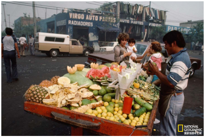 城中小摊
1984年08月，墨西哥城中，路人在一个街边小摊买水果。墨西哥城在当时快速发展，目前已成为世界第五大城市。摄影：Stephanie Maze
