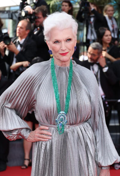 马斯克的妈妈Maye Musk 佩戴的项链来自Chopard 萧邦 Red Carpet 系列，共计603.9克拉祖母绿圆珠串连其上，中央镶嵌着一颗23.76克拉凸圆形黑色蛋白石，共计19.7克拉梯形切割托帕石、13.9克拉明亮式切割碧玺石、彩色蓝…