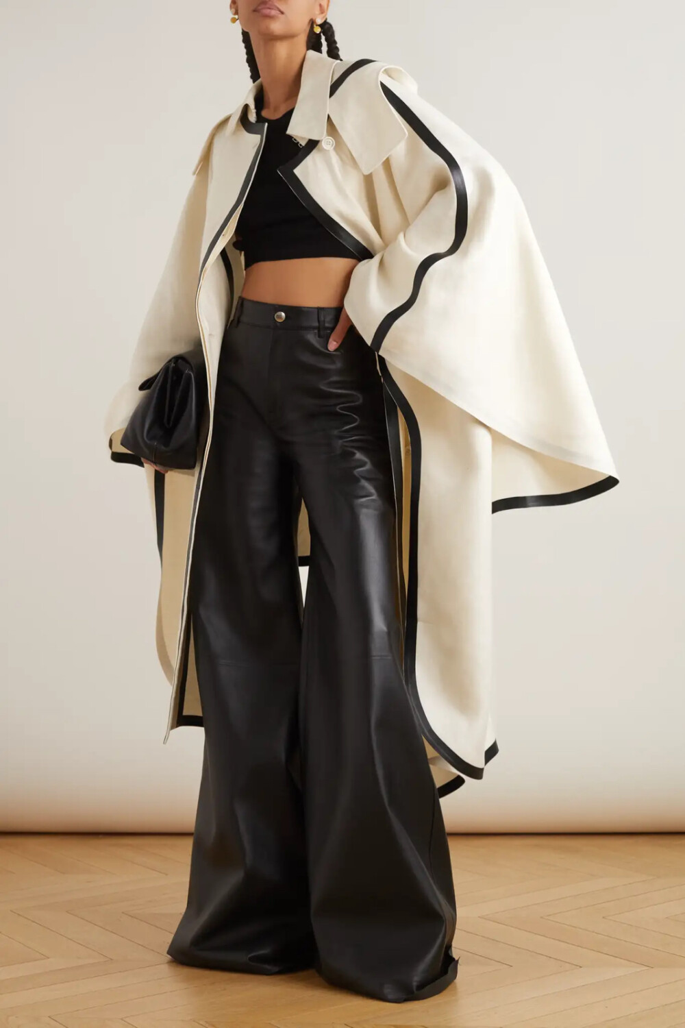 Chloé 这款外套以重磅亚麻帆布制成，披风效果版型醒目别致。衣身宽松而富有垂感，边缘粘合对比色条形皮革，轮廓鲜明，还有兜帽为你遮挡风雨。