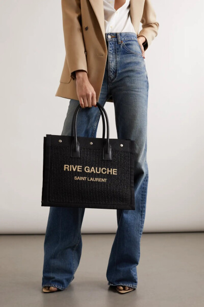 SAINT LAURENT 这款 “Rive Gauche” 手提包定能成为你珍藏多年的时髦单品。简约隽永的它诞生于意大利，以拉菲草和同色系帆布与皮革边饰精心制成，饰有大号刺绣字样。包身容量颇为宽敞，笔记本电脑、钱包与化妆包等…