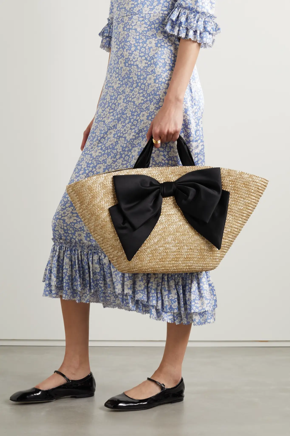 Eugenia Kim 这款 “Carlotta” 手提包以轻盈编织草制成，在原版基础上增添了醒目的缎布蝴蝶结，来呼应同样材质的黑色手柄。梯形包身内部空间充裕，可容纳毛巾和书本等日常随身物品。不妨带上时髦且实用的它前去游览风景名胜。
