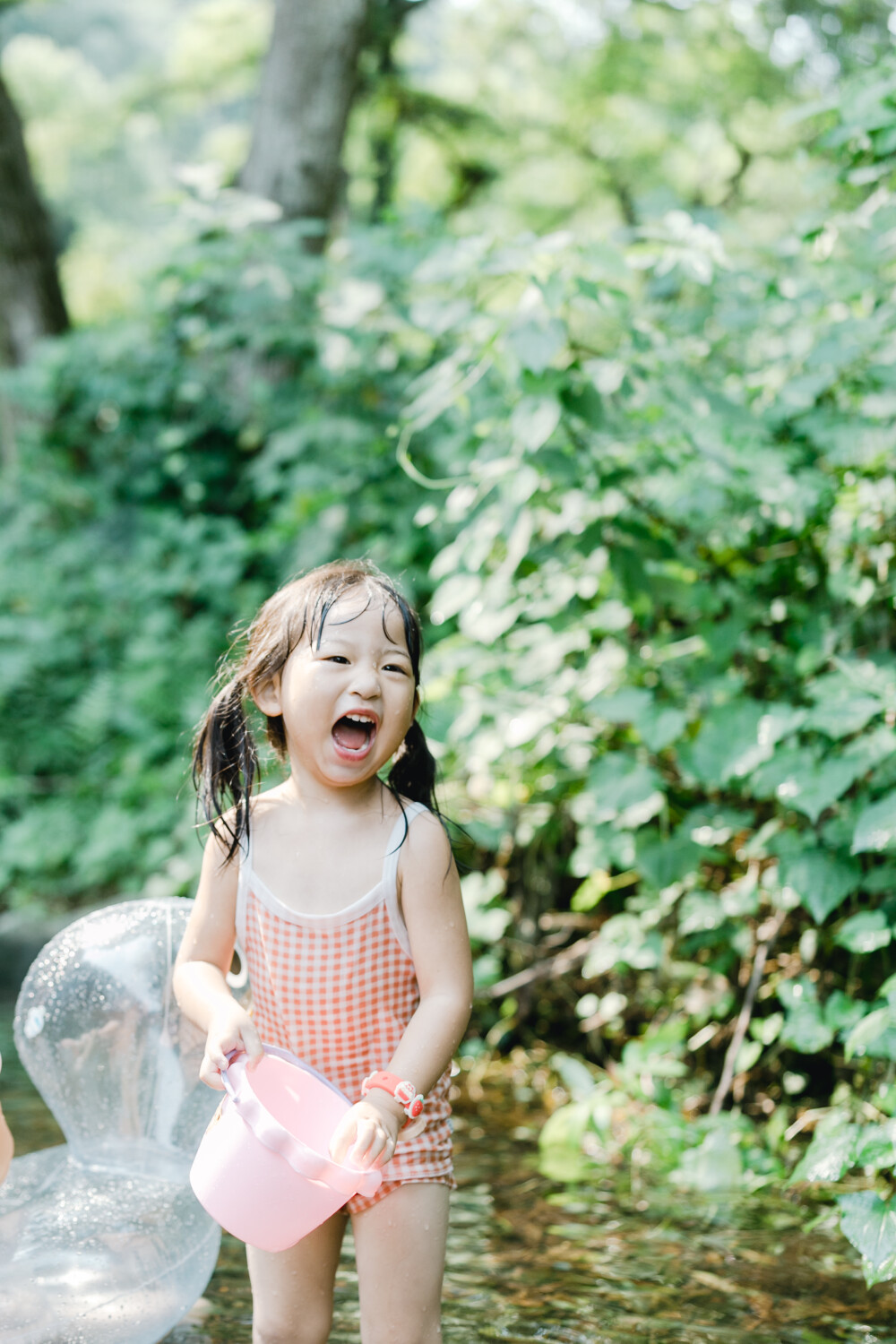 夏天总是要去九溪的
摄影：洪小漩
出镜：菲比和格格等
每年夏天，九溪都是必去之地。
曾经，打车是可以直达九溪烟树的。如今，想要驱车前往，必须提前预约。或是统一乘坐观光车进入。
今日份阿科出差，两个三口之家的出行便缺了一个壮劳力，少了一分从容。
三个大人提着装备吃食，外加菲比三不五时闹着要抱，我们便索性绝了步行进入的念头，半程观光车，半程徒步，总算找了一小片人不算多的水域。
阿科不在，张罗菲比的我显得十分狼狈。不过，小朋友玩得尽兴，别的也就无所谓了。
一只小桶、一把水枪、一个游泳圈、一个西瓜，夏天那味便有了七八分。剩下的便是聒噪的蝉鸣和潺潺的流水。这不，今日都齐了。