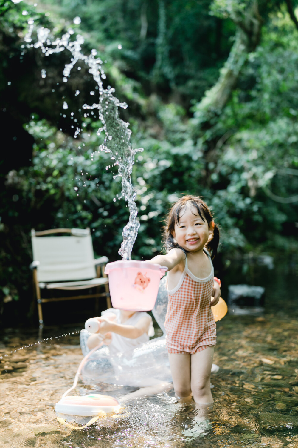 夏天总是要去九溪的
摄影：洪小漩
出镜：菲比和格格等
每年夏天，九溪都是必去之地。
曾经，打车是可以直达九溪烟树的。如今，想要驱车前往，必须提前预约。或是统一乘坐观光车进入。
今日份阿科出差，两个三口之家的出行便缺了一个壮劳力，少了一分从容。
三个大人提着装备吃食，外加菲比三不五时闹着要抱，我们便索性绝了步行进入的念头，半程观光车，半程徒步，总算找了一小片人不算多的水域。
阿科不在，张罗菲比的我显得十分狼狈。不过，小朋友玩得尽兴，别的也就无所谓了。
一只小桶、一把水枪、一个游泳圈、一个西瓜，夏天那味便有了七八分。剩下的便是聒噪的蝉鸣和潺潺的流水。这不，今日都齐了。