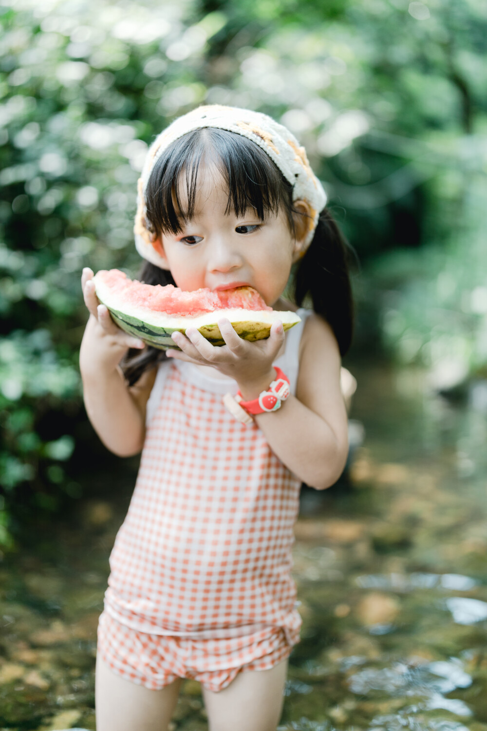 夏天总是要去九溪的
摄影：洪小漩
出镜：菲比和格格等
每年夏天，九溪都是必去之地。
曾经，打车是可以直达九溪烟树的。如今，想要驱车前往，必须提前预约。或是统一乘坐观光车进入。
今日份阿科出差，两个三口之家的出行便缺了一个壮劳力，少了一分从容。
三个大人提着装备吃食，外加菲比三不五时闹着要抱，我们便索性绝了步行进入的念头，半程观光车，半程徒步，总算找了一小片人不算多的水域。
阿科不在，张罗菲比的我显得十分狼狈。不过，小朋友玩得尽兴，别的也就无所谓了。
一只小桶、一把水枪、一个游泳圈、一个西瓜，夏天那味便有了七八分。剩下的便是聒噪的蝉鸣和潺潺的流水。这不，今日都齐了。