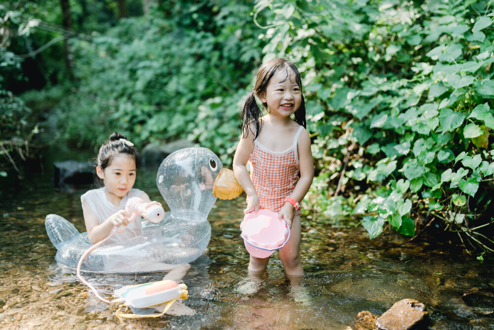 夏天总是要去九溪的
摄影：洪小漩
出镜：菲比和格格等
每年夏天，九溪都是必去之地。
曾经，打车是可以直达九溪烟树的。如今，想要驱车前往，必须提前预约。或是统一乘坐观光车进入。
今日份阿科出差，两个三口之家的出行便缺了一个壮劳力，少了一分从容。
三个大人提着装备吃食，外加菲比三不五时闹着要抱，我们便索性绝了步行进入的念头，半程观光车，半程徒步，总算找了一小片人不算多的水域。
阿科不在，张罗菲比的我显得十分狼狈。不过，小朋友玩得尽兴，别的也就无所谓了。
一只小桶、一把水枪、一个游泳圈、一个西瓜，夏天那味便有了七八分。剩下的便是聒噪的蝉鸣和潺潺的流水。这不，今日都齐了。