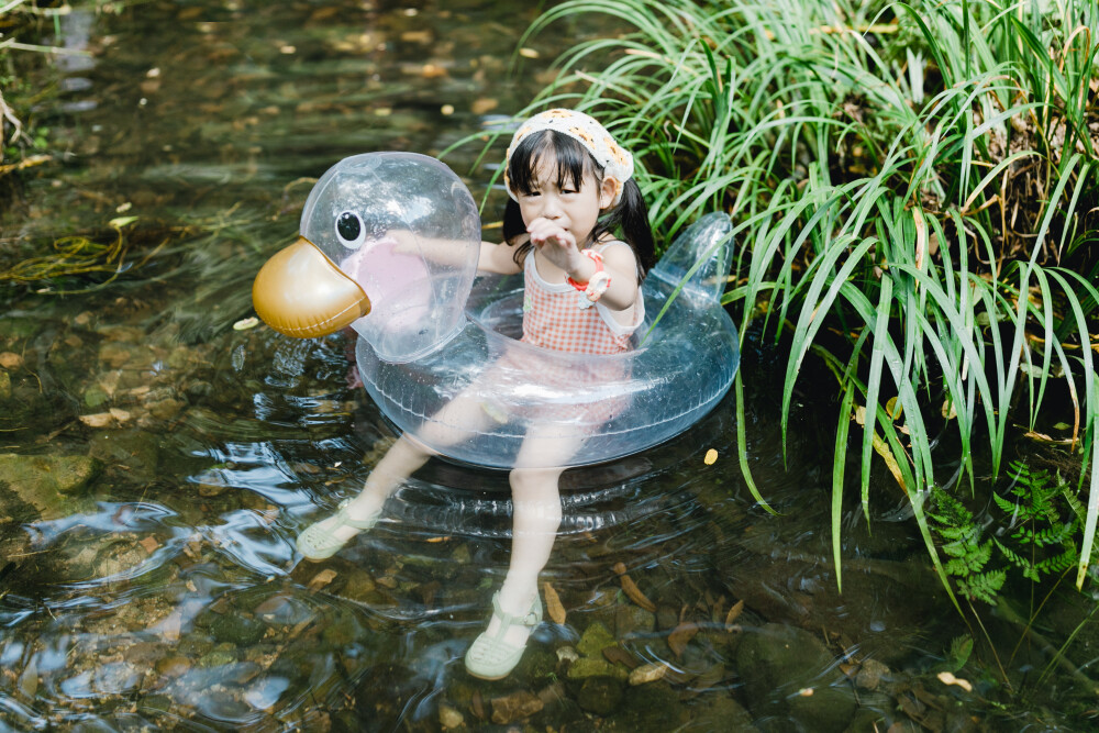 夏天总是要去九溪的
摄影：洪小漩
出镜：菲比和格格等
每年夏天，九溪都是必去之地。
曾经，打车是可以直达九溪烟树的。如今，想要驱车前往，必须提前预约。或是统一乘坐观光车进入。
今日份阿科出差，两个三口之家的出行便缺了一个壮劳力，少了一分从容。
三个大人提着装备吃食，外加菲比三不五时闹着要抱，我们便索性绝了步行进入的念头，半程观光车，半程徒步，总算找了一小片人不算多的水域。
阿科不在，张罗菲比的我显得十分狼狈。不过，小朋友玩得尽兴，别的也就无所谓了。
一只小桶、一把水枪、一个游泳圈、一个西瓜，夏天那味便有了七八分。剩下的便是聒噪的蝉鸣和潺潺的流水。这不，今日都齐了。