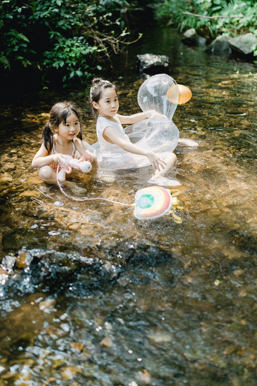 夏天总是要去九溪的
摄影：洪小漩
出镜：菲比和格格等
每年夏天，九溪都是必去之地。
曾经，打车是可以直达九溪烟树的。如今，想要驱车前往，必须提前预约。或是统一乘坐观光车进入。
今日份阿科出差，两个三口之家的出行便缺了一个壮劳力，少了一分从容。
三个大人提着装备吃食，外加菲比三不五时闹着要抱，我们便索性绝了步行进入的念头，半程观光车，半程徒步，总算找了一小片人不算多的水域。
阿科不在，张罗菲比的我显得十分狼狈。不过，小朋友玩得尽兴，别的也就无所谓了。
一只小桶、一把水枪、一个游泳圈、一个西瓜，夏天那味便有了七八分。剩下的便是聒噪的蝉鸣和潺潺的流水。这不，今日都齐了。