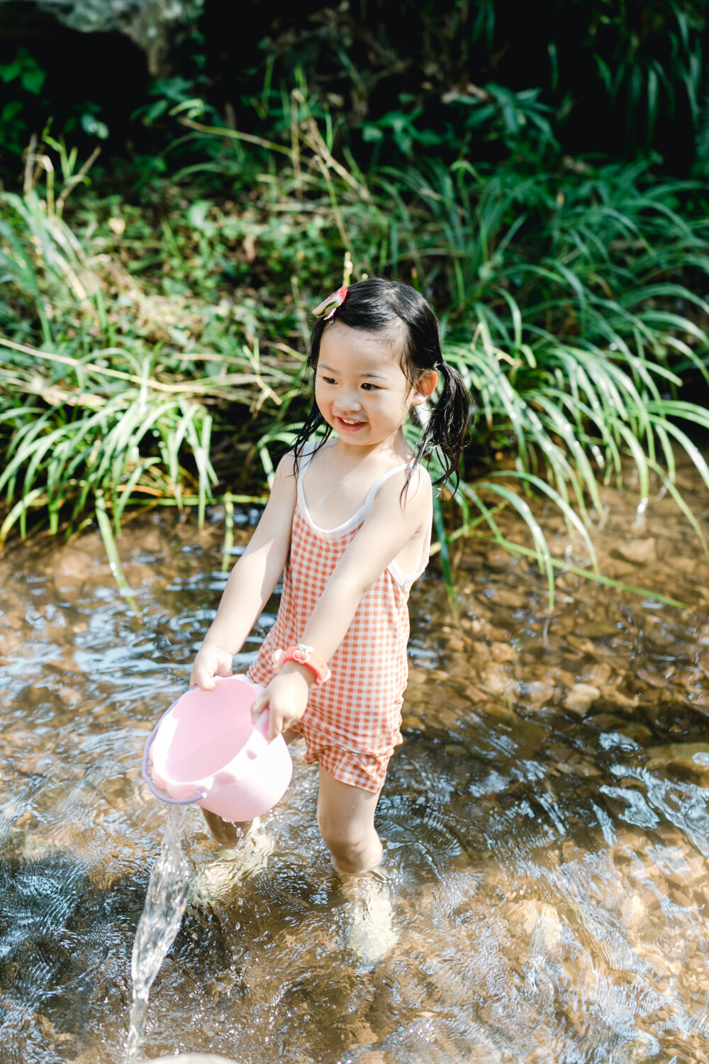 夏天总是要去九溪的
摄影：洪小漩
出镜：菲比和格格等
每年夏天，九溪都是必去之地。
曾经，打车是可以直达九溪烟树的。如今，想要驱车前往，必须提前预约。或是统一乘坐观光车进入。
今日份阿科出差，两个三口之家的出行便缺了一个壮劳力，少了一分从容。
三个大人提着装备吃食，外加菲比三不五时闹着要抱，我们便索性绝了步行进入的念头，半程观光车，半程徒步，总算找了一小片人不算多的水域。
阿科不在，张罗菲比的我显得十分狼狈。不过，小朋友玩得尽兴，别的也就无所谓了。
一只小桶、一把水枪、一个游泳圈、一个西瓜，夏天那味便有了七八分。剩下的便是聒噪的蝉鸣和潺潺的流水。这不，今日都齐了。