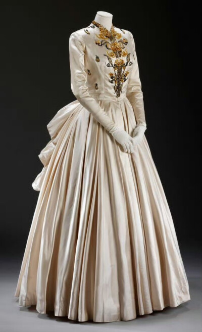 法国服装设计师杰奎斯.菲斯（Jacques Fath ，1912-1954）的女裙设计。菲斯成长于艺术世家，1937 年在巴黎开设了自己的工作室。菲斯从古典服饰、剧院戏服及芭蕾舞裙中汲取了很多灵感，突出的大领口、收腰设计、不对称…