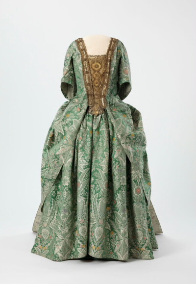 一件约1720年，保存完好的曼图亚女袍。青绿色织锦上布满繁复奇趣的花草纹样，衣襟边缘装饰金线，胸片也被金线做成的网纱、刺绣和立体花朵塞得满满当当，着实华丽。 ​​​