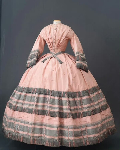 一件1850年代日装，光泽如瓷器的淡粉色缎子上装饰青绿色的饰带与流苏，清新柔和的色彩配上大蓬蓬裙，显得很可爱。 ​​​