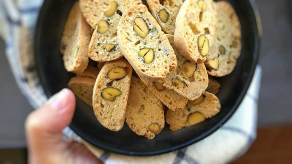 意大利甜品 Cantuccini 意式杏仁脆饼 诞生于中世纪托斯卡尼地区的传统点心，由各类干果或坚果制成的杏仁风味硬饼干，从里到外酥香爽脆。被咬断时还会发出细小的声响，因此命名时便参考了在意大利语中有着“微弱的歌声”这个意思的单=词“Cantocci/Cantucci”。由于太硬，意大利人常常把它浸在餐后葡萄酒(例如意大利甜白葡萄酒“Vin Santo”)或咖啡等饮料中，泡软之后再取出食用。添加了杏仁的意式长条饼干，是下午茶的极佳伴侣，蘸着咖啡或茶更是别有一番风味。加入杏仁也可以看做 Cantuccini Toscani O Biscotti di Prato