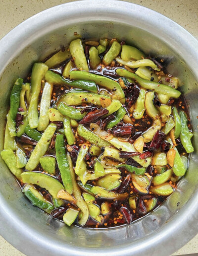 黄瓜去籽用糖、盐放一两个小时腌出水，然后把水挤干，配料干辣椒，蒜姜花椒用油小火炸香，放不放凉都行，到黄瓜里，其他调料，少盐，多放糖，香醋，生抽，味精，吃饭的小勺子两勺蚝油，在倒些水，放大盆里搅拌到糖化…