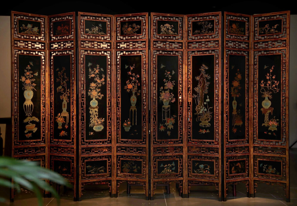 此屏风以血檀榫卯传制木胎底，湘妃竹为材，竹纹如泪，暗合“人天同醉”之境。匠作之精见诸结构之间，无钉无胶，以木性相契，成千年对话之姿。漆雕、镶嵌、漆绘多重技法施用，漆面如镜，雕纹若游，镶嵌之物皆经人手打磨，温润如玉。
正反装八幅片，图饰以「百草」「清供」「山水」「雅趣」为魂，笔触间见文人意趣。