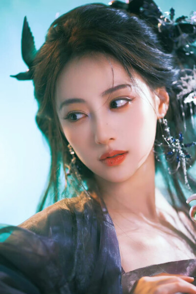 胡连馨｜烟霭朦胧处，她似从水墨里走出的仙。
银饰是星子落在发上，素衣糅着云的缥缈。
唇上那朵绯色，是风路过桃林时，偷偷藏下的春色。