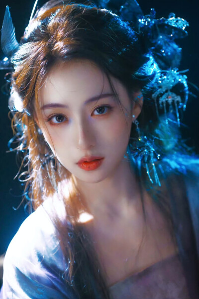 胡连馨｜烟霭朦胧处，她似从水墨里走出的仙。
银饰是星子落在发上，素衣糅着云的缥缈。
唇上那朵绯色，是风路过桃林时，偷偷藏下的春色。