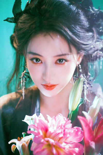 胡连馨｜烟霭朦胧处，她似从水墨里走出的仙。
银饰是星子落在发上，素衣糅着云的缥缈。
唇上那朵绯色，是风路过桃林时，偷偷藏下的春色。