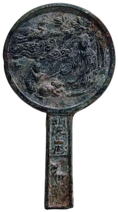 ▲ [金] 圆形平素缘仙鹤人物故事纹柄镜直径8.3厘米，柄长6.9厘米 
首都博物馆藏 