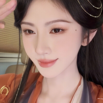 鬓间珠链轻曳颊畔柔痣，眉目浸着温软桃光，朱衣衬人温婉如画。
