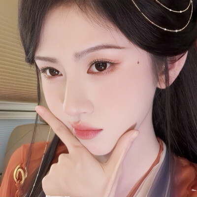 鬓间珠链轻曳颊畔柔痣，眉目浸着温软桃光，朱衣衬人温婉如画。
