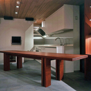 1階の奥は阪根氏がデザインした厚い天板のダイニングテーブルが置かれたLDK。天井や造り付けの家具に、マホガニーやパドオクやオバンコールといった高級木材が使われ、狭いながらもラグジュアリー感が漂う室内に仕上がっている。