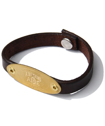 A BATHING APE复古风格的全新力作LEATHER BRACELET，正面的圆形金属雕刻有A BAHTING APE的品牌标识，搭配以复古味道的牛皮手环看起来颇具日式精致的手工艺风格。