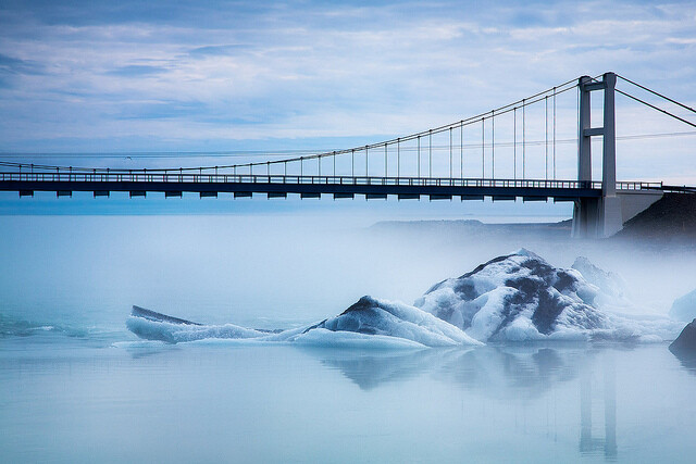 A bridge crosses the Ice Lagoon known as Jökulsárlón in the South of Iceland. The ice lagoon is full of large pieces of ice from glaciers that run into the lagoon. The lagoon leads on to a black sandy beach, creating a spectacular effect with the ice.