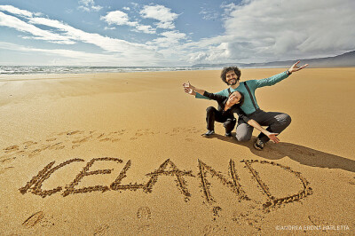 快乐的旅行者在沙地上写下iceland