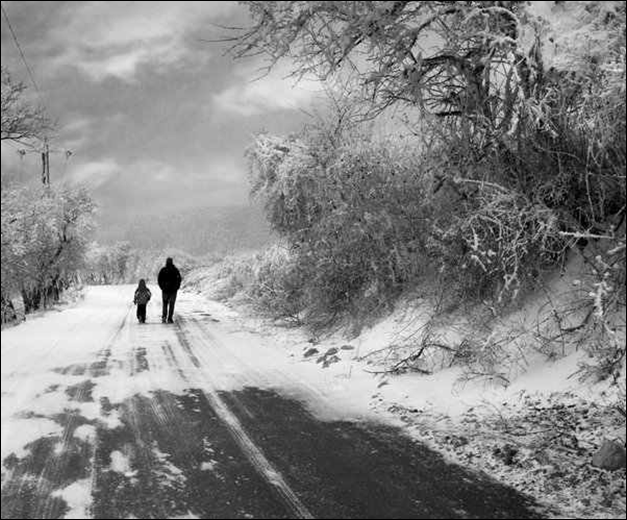 行走在雪地里的父子。道路很滑。